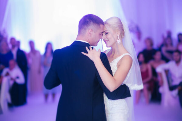 Portrait of first dance of stylish wedding couple. Handsome groom and elegant bride in the restaurant.